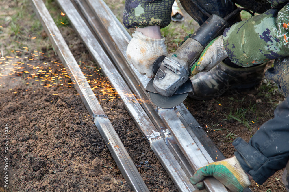 Obraz premium A worker grinds metal at a construction site.
