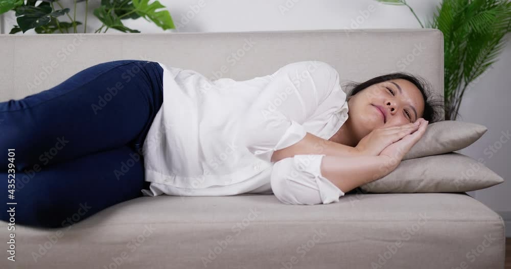 Young woman lying on sofa watching on TV in living room Young woman lying on sofa watching on TV in living room