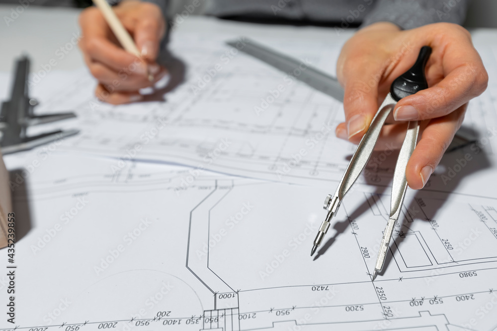 The architect measures with a dividers for drawing on paper. The designer draws a sketch of the room. The architect measures with a dividers for drawing on paper. The designer draws a sketch of the room.