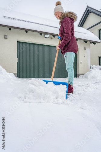 Teenager, junges Mädchen  beim Schnee Schippen vor dem Haus photo