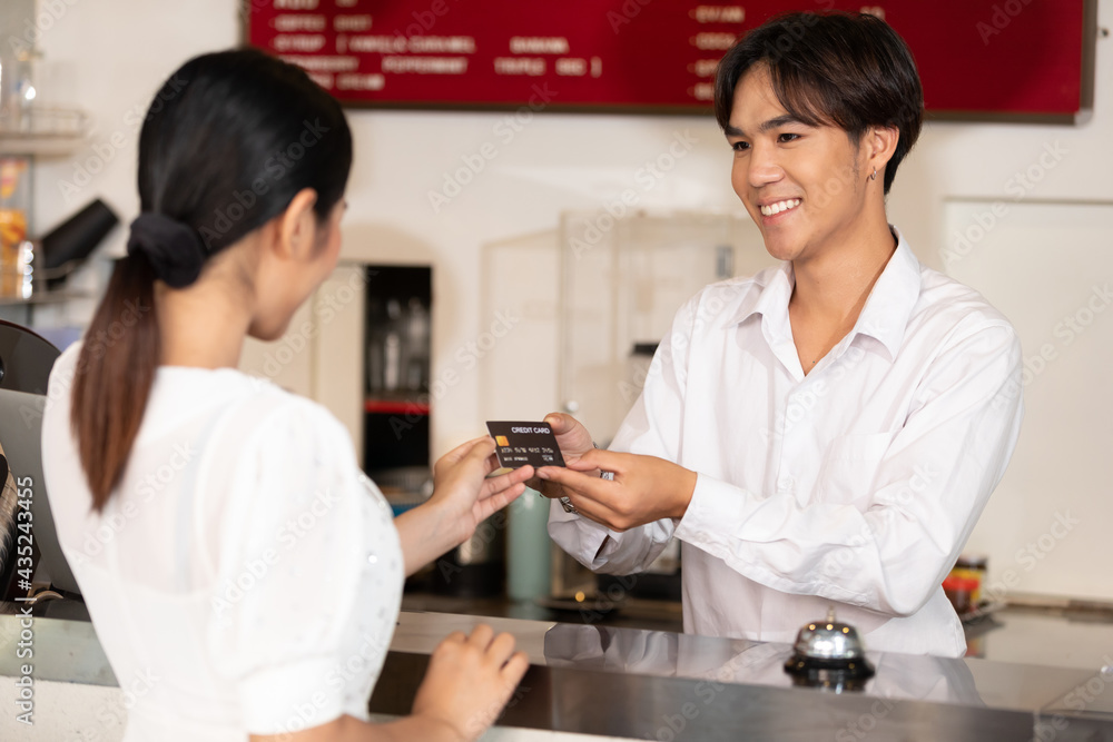 male receptionist or hotel front desk smiling and receiving credit card from woman guest male receptionist or hotel front desk smiling and receiving credit card from woman guest