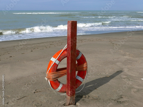 un brillante salvagente arancione con lo sfondo del mare invernale sulla spiaggia