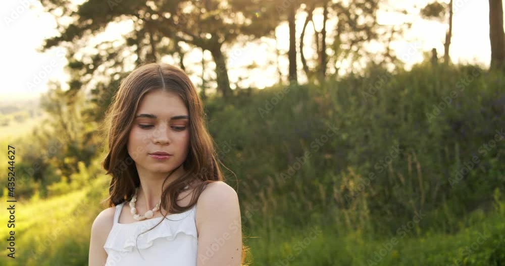 Attractive European chestnut teen girl with natural make-up looks into the camera in nature on a sunny day. Attractive European chestnut teen girl with natural make-up looks into the camera in nature on a sunny day.