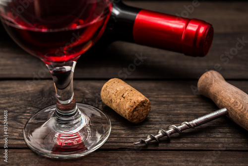 Bottle of red wine with a glass of red wine and cork on an old wooden table. Close up view, focus on the cork