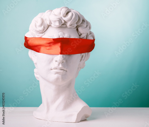 Plaster head with eyes covered red satin ribbon on blue background. Avoid problems concept. photo