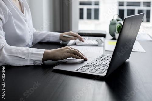 A close-up businesswoman using her laptop's touchpad, using her laptop to search the Internet and chat with friends and business partners using a messaging program. Concept of technology.
