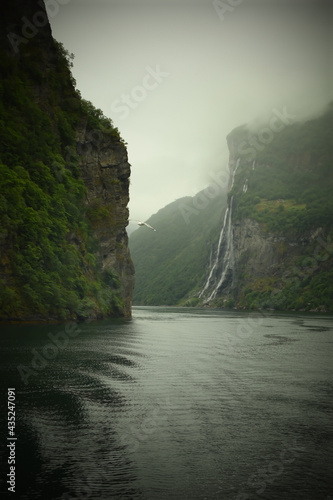 Strait, mountain bay with waterfalls in cloudy weather