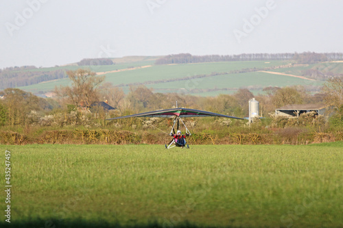Canvas-taulu Ultralight airplane landing on a grass strip