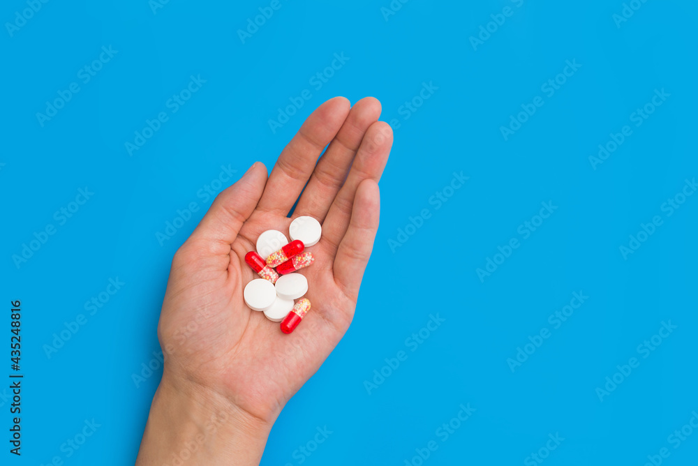 medicinal pills white and red on a person's hand on a blue background copy the space. the concept of health preservation, medical treatment of the disease medicinal pills white and red on a person's hand on a blue background copy the space. the concept of health preservation, medical treatment of the disease