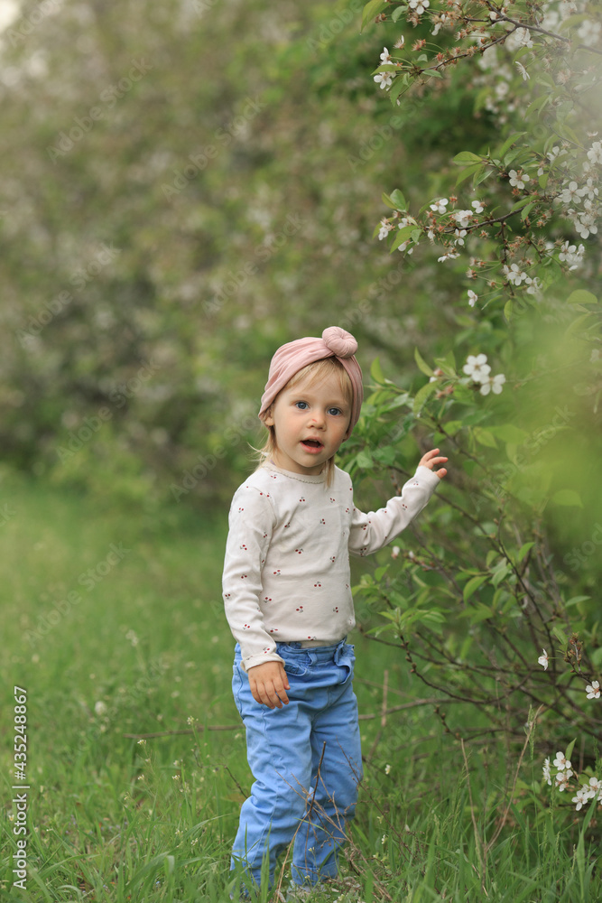 a beautiful child touches a white flower and opens his mouth, surprised a beautiful child touches a white flower and opens his mouth, surprised