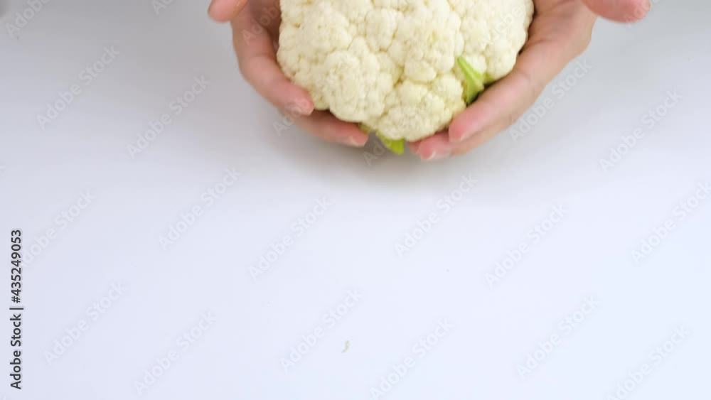 The man's hand slowly moved Cauliflower into on a white background. The man's hand slowly moved Cauliflower into on a white background.