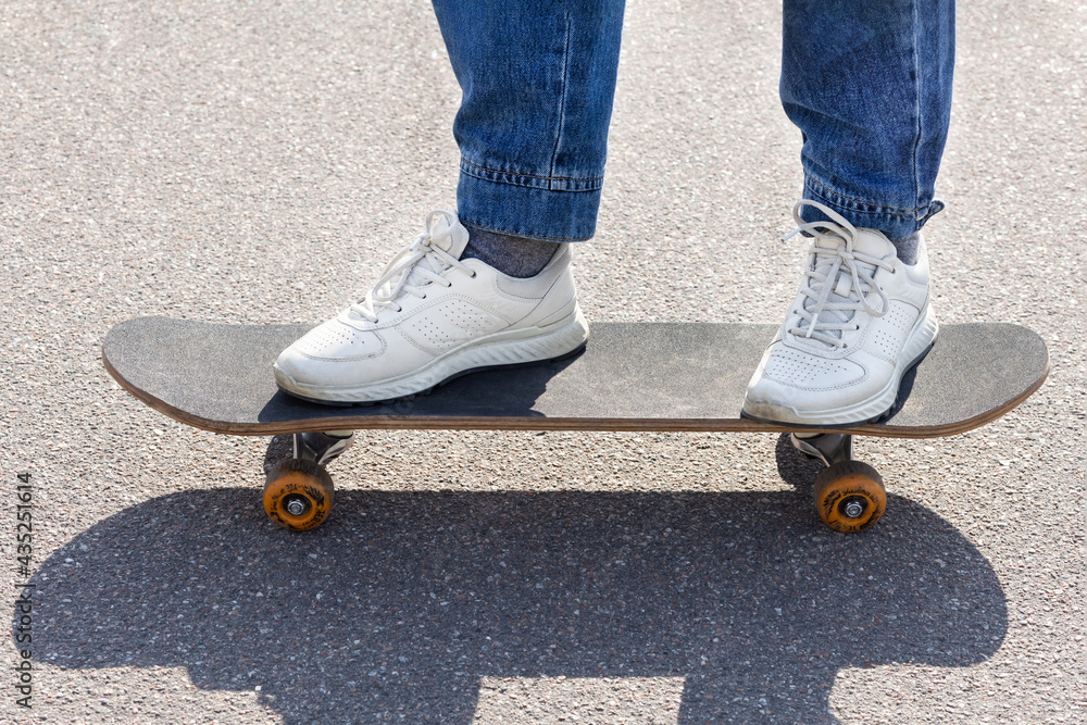 closeup female feet in white sneakers on skateboard on asphalt, on track. woman legs on board at skatepark. urban active extreme sport in the city. closeup female feet in white sneakers on skateboard on asphalt, on track. woman legs on board at skatepark. urban active extreme sport in the city.
