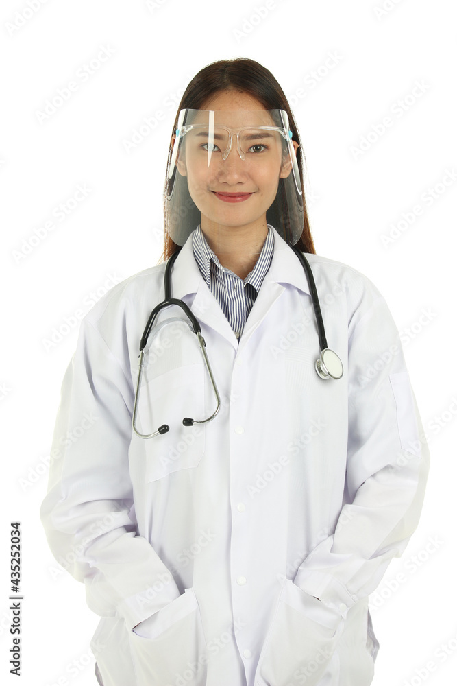 Fototapeta premium Portrait of smiling young beautiful Asian female medical doctor in lab coat with stethoscope wearing face shield, standing isolated on white background.
