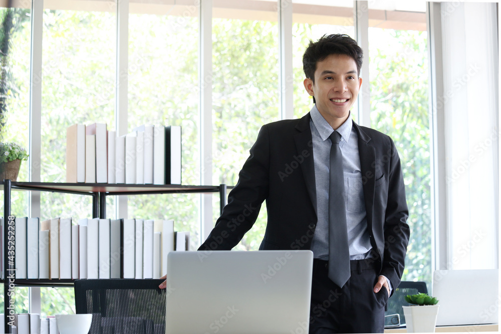 Portrait of smiling young Asian businessman standing at office working desk, happy workplace concept. Portrait of smiling young Asian businessman standing at office working desk, happy workplace concept.