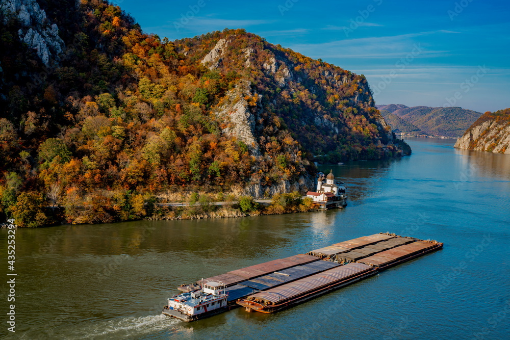 Cargo ship passing by Mraconia monastery on Romanian side of Danube river Djerdap gorge