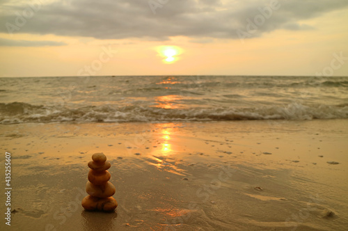 Closeup stack of balanced pebble stones on the sunset beach against splashing waves  © jobi_pro