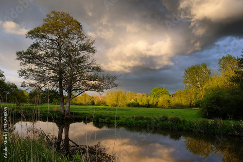 Stormy skies and rain as the sun sets over the River Wey and meadows in Godalming, Surrey, UK photo