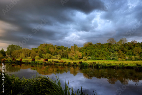 Stormy skies as the sun sets over the River Wey and meadows in Godalming, Surrey, UK