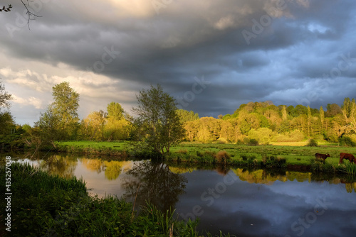 Stormy skies as the sun sets over the River Wey and meadows in Godalming, Surrey, UK