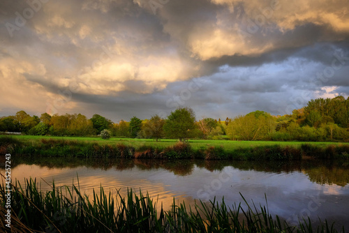 Stormy skies as the sun sets over the River Wey and meadows in Godalming  Surrey  UK