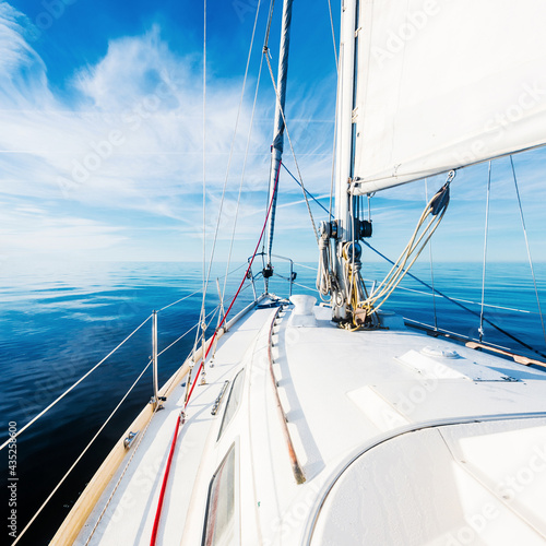 White sloop rigged yacht sailing in an open Baltic sea on a sunny summer day. View from the deck to the bow. Idyllic seascape. Vacations, cruise, regatta, sport, leisure activity, recreation photo