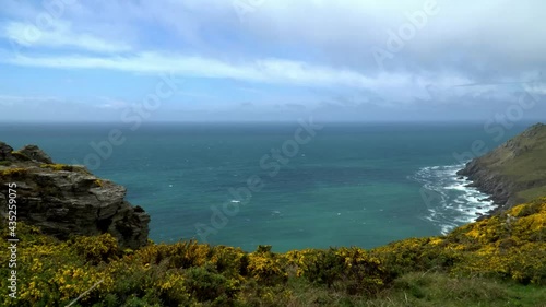 Wallpaper Mural Real time 4k footage pan across dramatic UK Devon coast line. Waves crash onto cliffs below and coarse landscape in foreground. Bright blue and green crystal clear sea with blue and cloudy sky above Torontodigital.ca