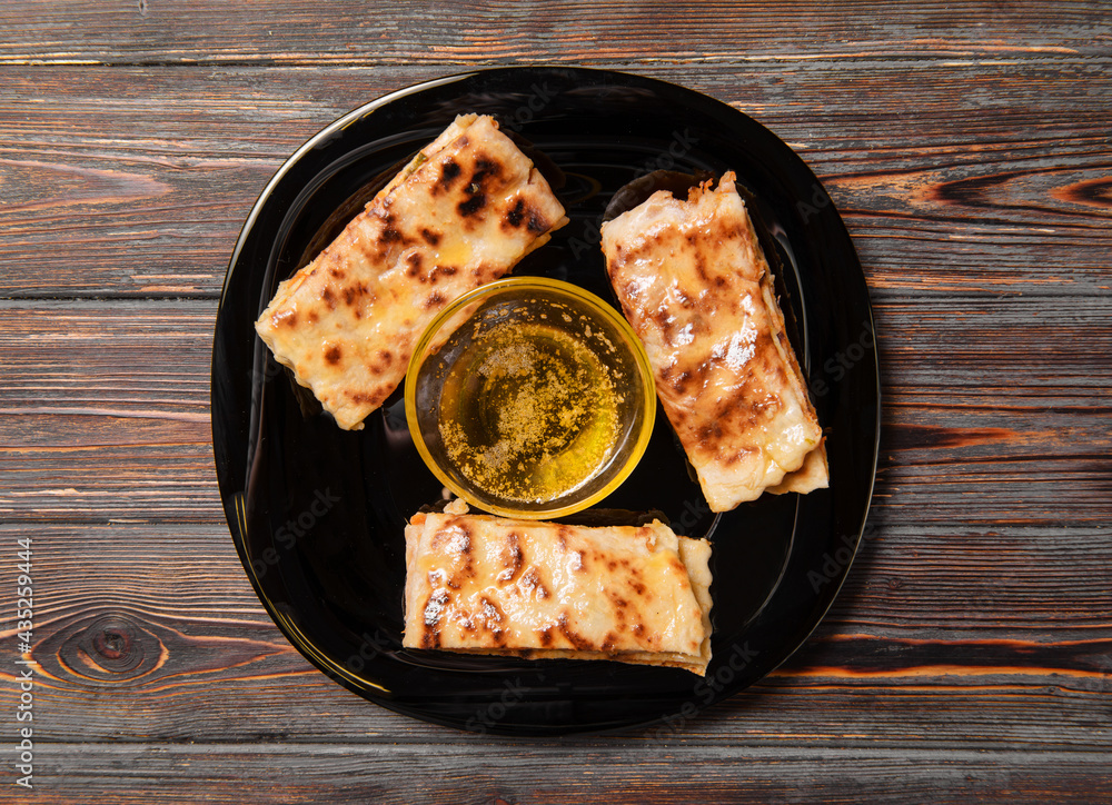  tortillas with pumpkin and butter on a black plate on a dark wooden background, top view