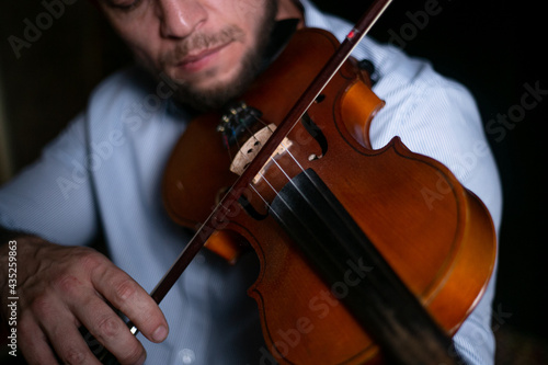 A man plays a violin close-up on a black background