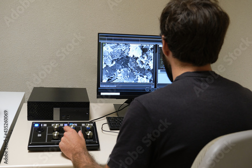 Fototapeta Naklejka Na Ścianę i Meble -  Young man scientist working with scanning electron microscope. Laboratory technician observing samples with a SEM.