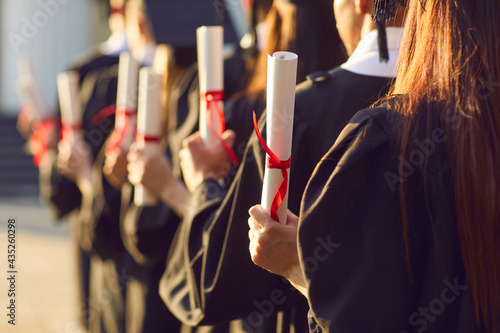 Obraz na plátně Student holding diploma degree certificate scroll at college or university graduation ceremony