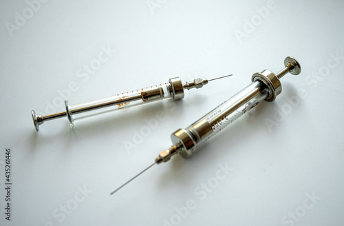 Two old glass syringes with needles on white isolate