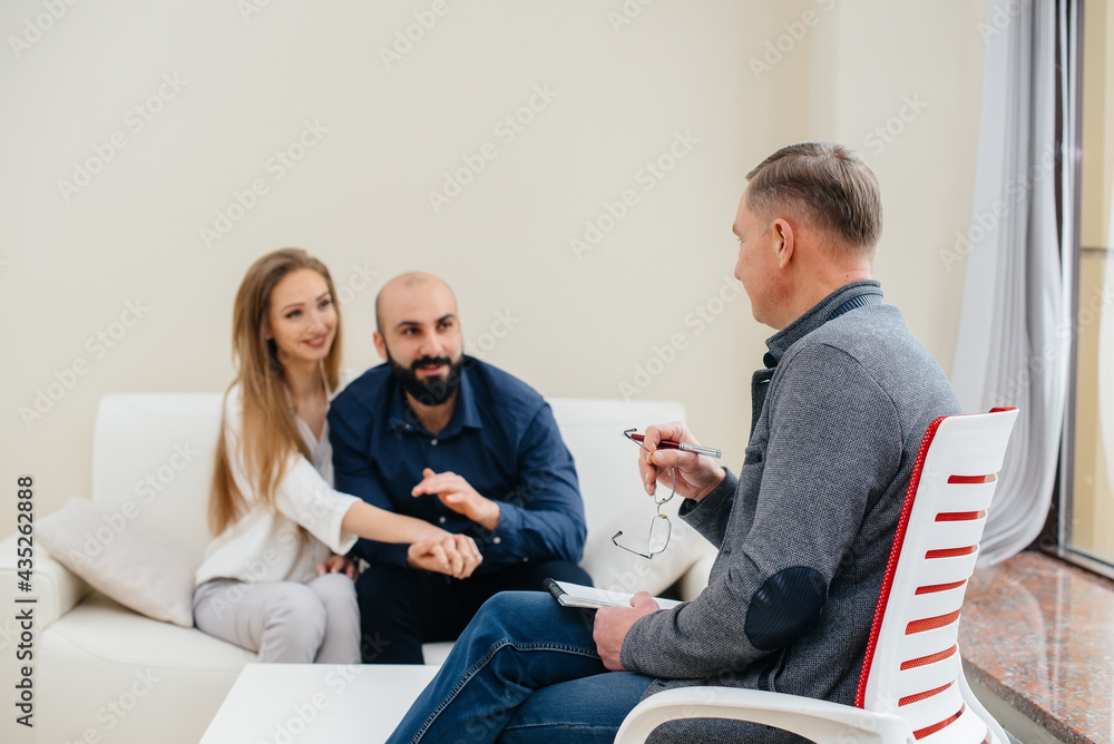 Obraz premium A young happy married couple of men and women talk to a psychologist at a therapy session. Psychology.