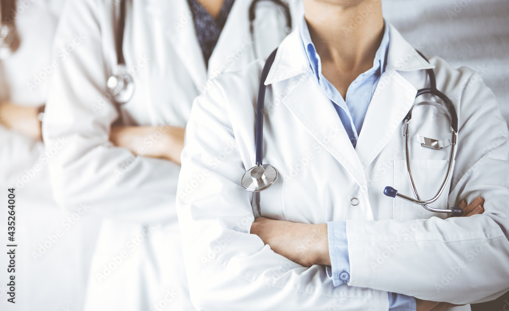 Group of modern doctors standing as a team with arms crossed in sunny hospital and ready to help patients. Medical help, insurance in health care Group of modern doctors standing as a team with arms crossed in sunny hospital and ready to help patients. Medical help, insurance in health care