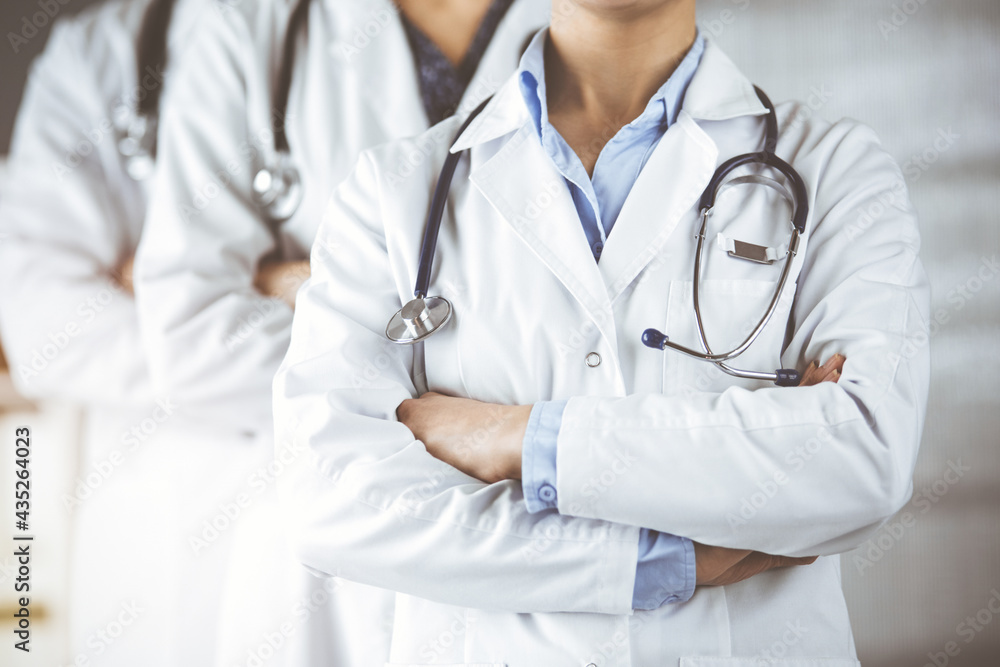 Group of modern doctors standing as a team with arms crossed in sunny hospital and ready to help patients. Medical help, insurance in health care Group of modern doctors standing as a team with arms crossed in sunny hospital and ready to help patients. Medical help, insurance in health care