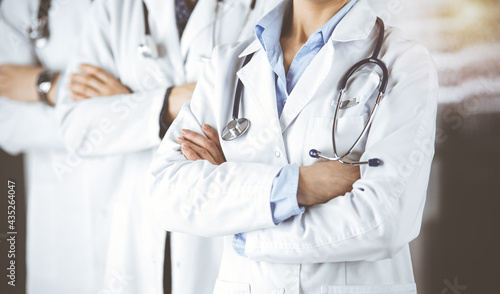 Group of modern doctors standing as a team with arms crossed in sunny hospital and ready to help patients. Medical help, insurance in health care