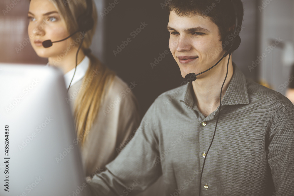Businessman talking by headset while sitting in sunny office. Telemarketing concept Businessman talking by headset while sitting in sunny office. Telemarketing concept