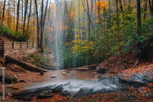 Behind a waterfall known as Moore Cove Falls  looking out towards the colorful, lush fall foliage of Pisgah National Forest, Transylvania County 