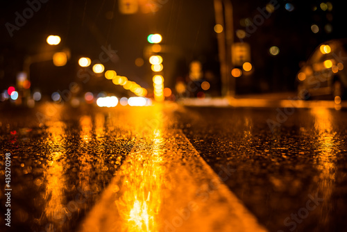 Rainy night in the big city, the glowing lights of approaching cars. View of the level of the dividing line