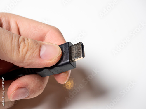 In the male hand is a black hdmi cable. Cable for connecting devices