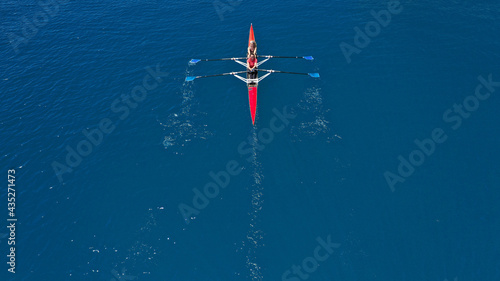 Aerial drone top down photo of sport canoe operated by team of young women in emerald calm sea waters