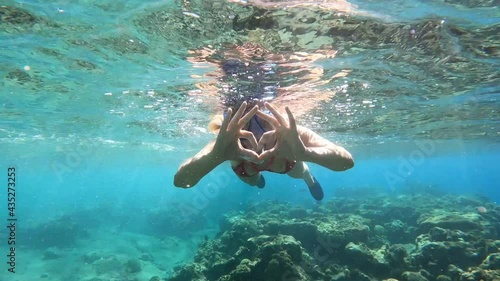 woman in sea on face snorkelling mask show by hands heart big love and declaration of love, after two thumbs up super,. trip into water all underwater world to see fish in vacation photo