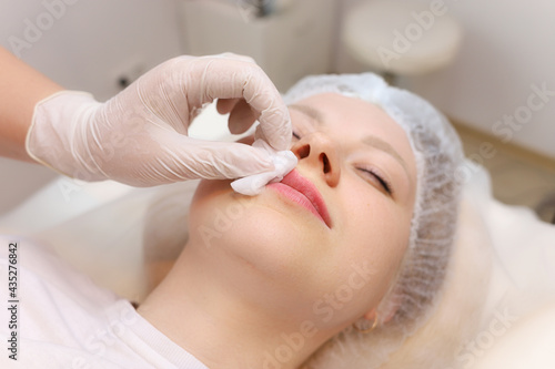 A master cosmetologist wipes blood droplets from his lips after a shot of hyaluronic acid © Roman