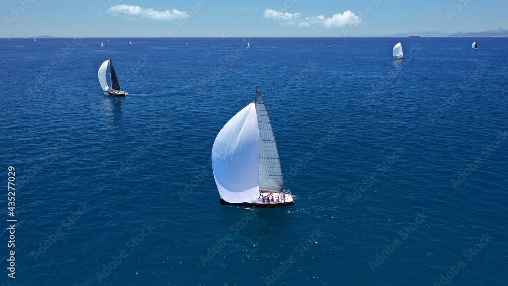 Aerial drone top down photo of beautiful sail boat with trained crew cruising in deep blue Aegean sea