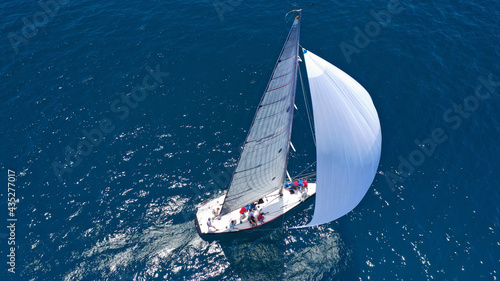Aerial drone top down photo of beautiful sail boat with trained crew cruising in deep blue Aegean sea © aerial-drone
