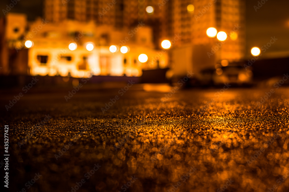 Rainy night in the big city, the light from the lanterns in the courtyard. View from the level of asphalt Rainy night in the big city, the light from the lanterns in the courtyard. View from the level of asphalt