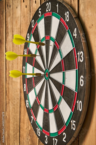 Darts game. Throwing darts at the target. Three yellow darts hit the target