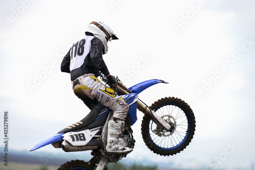 A motorcycle racer in a jump in the air. Side view. Selective focus. Copy space.