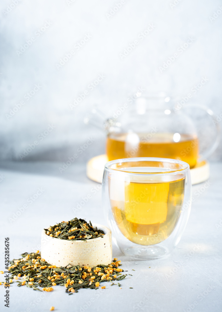 Japanese green tea Genmaicha.Tea leaves with fried brown rice on a bright gray background with a shadow.Slimming trend tea concept. a cup of tea. brew a transparent teapot Japanese green tea Genmaicha.Tea leaves with fried brown rice on a bright gray background with a shadow.Slimming trend tea concept. a cup of tea. brew a transparent teapot
