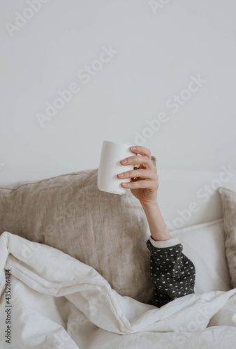 good morning - a woman's hand and a cup from under the blanket