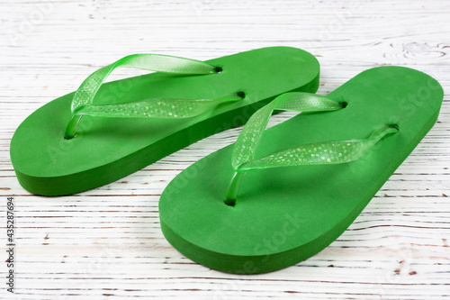 green rubber slippers on a white wooden background